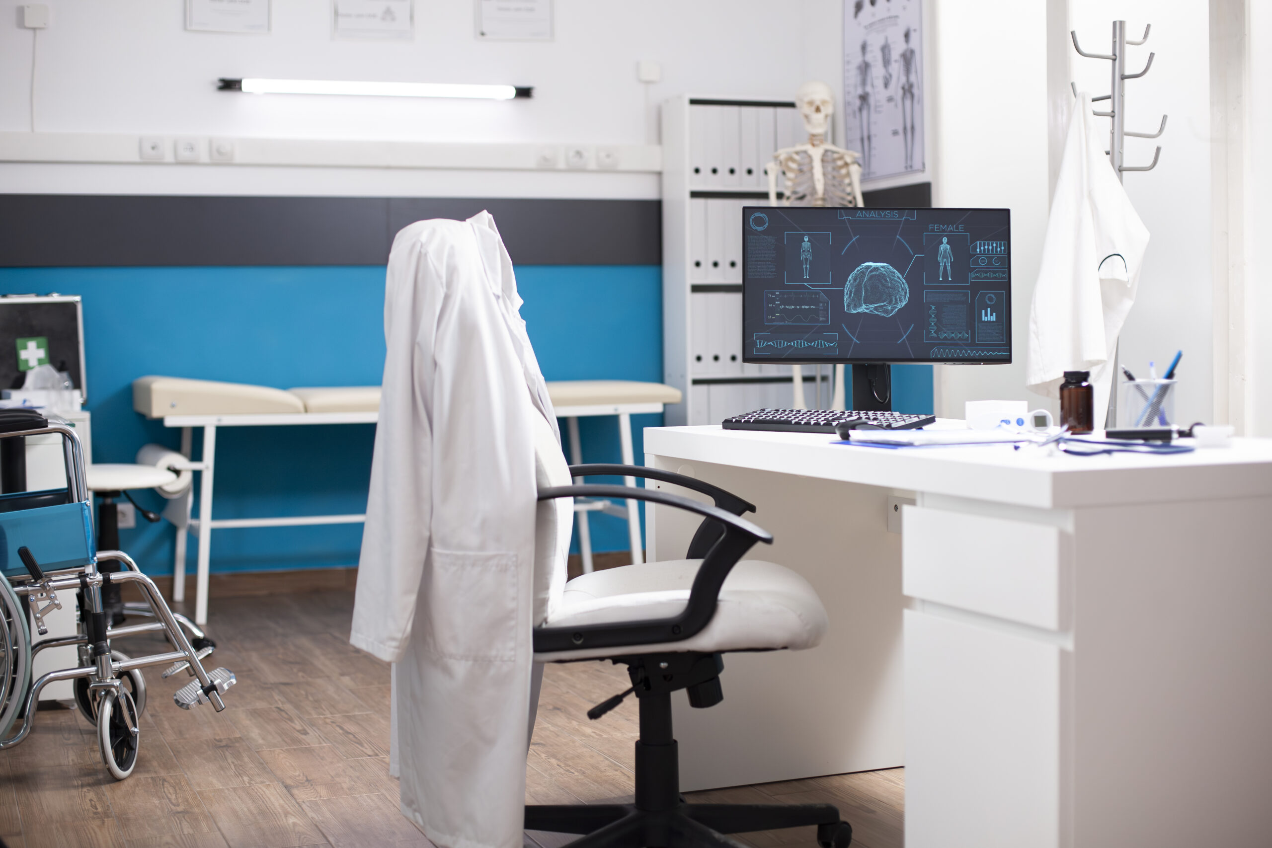 Modern clinic room displays computer monitor with neurology exam results placed on clean table with healthcare files nearby. Medical office setup supports neuroscience research and analysis.